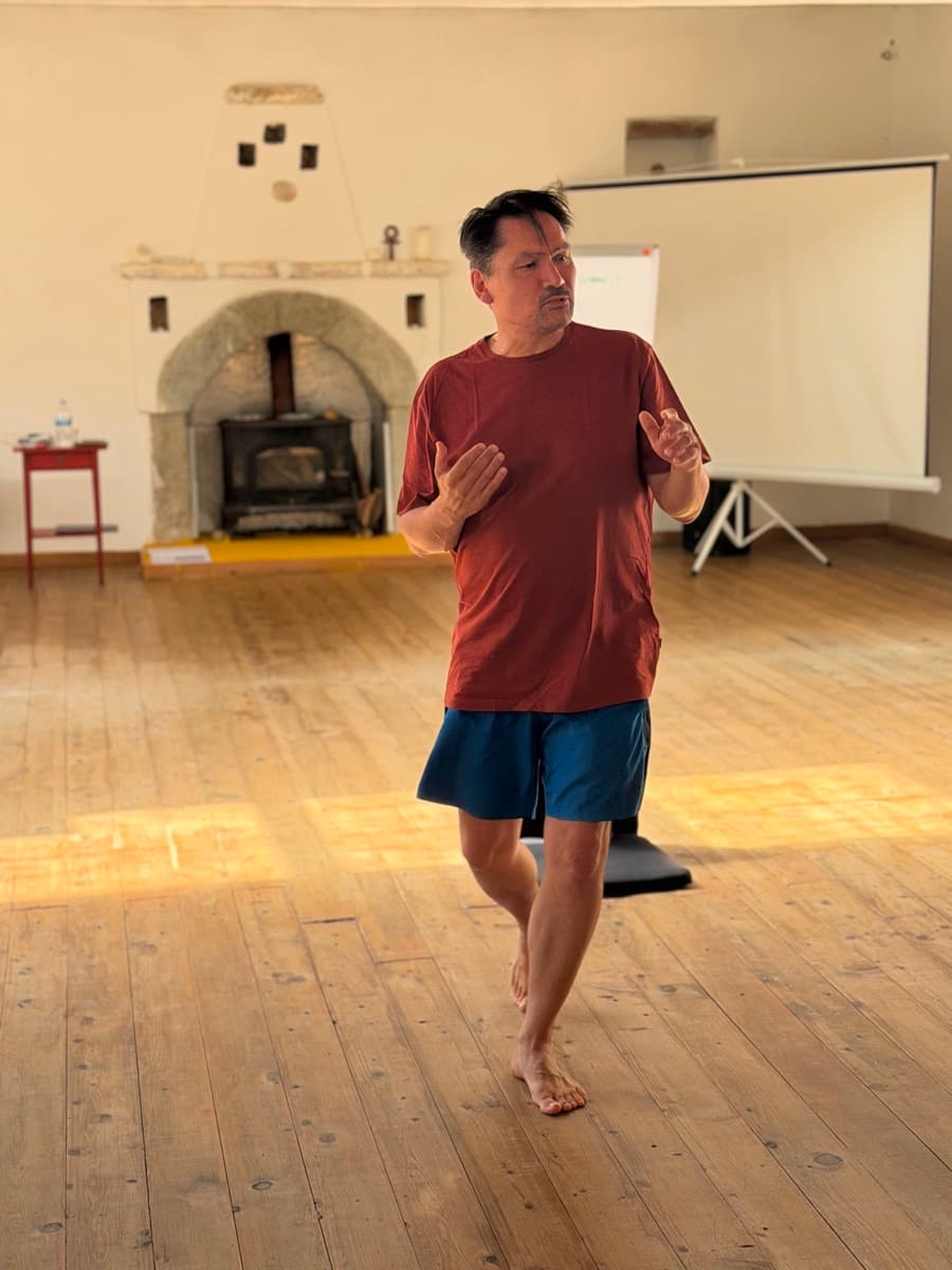 A teacher walking barefoot across a training room floor, demonstrating a movement pattern.